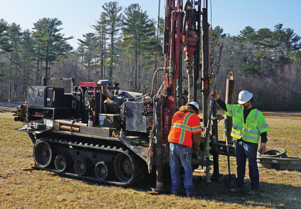 Two men operating a drill rig in a field.
