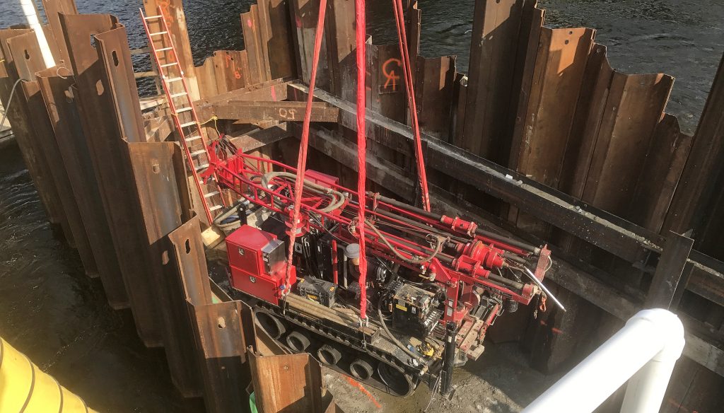 Drill rig being lowered onto job site with water around