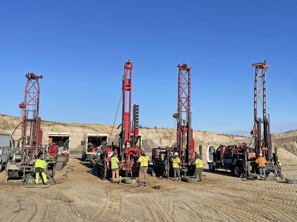 4 drill rigs side by side with people working on them